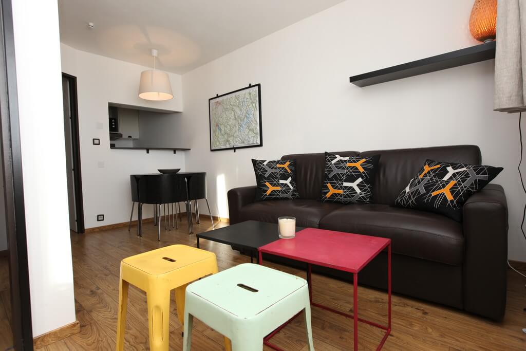 Lounge with black leather sofa and colourful stools in Apartment Alpages Charming, Avoriaz
