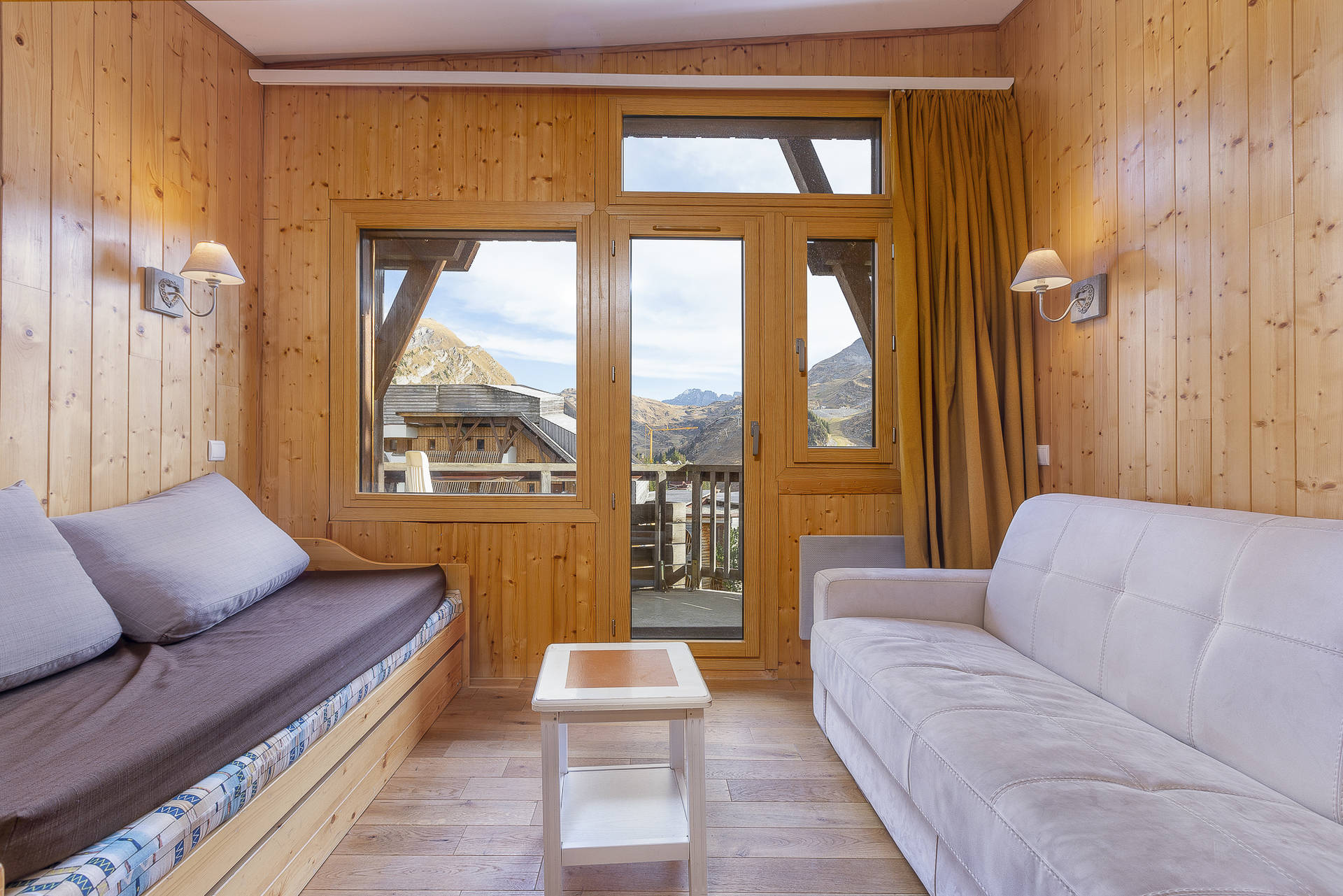 Wood-panelled lounge with sofa beds and balcony door in Apartment Chapka, Avoriaz
