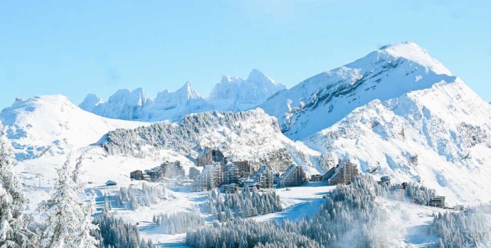 Avoriaz village nestled among frosted pine forest and snowy Portes du Soleil peaks under a clear blue sky