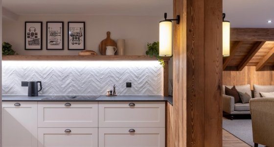 Kitchen with white cabinets, herringbone splashback and timber pillar in Apartment Le Stade, Morzine