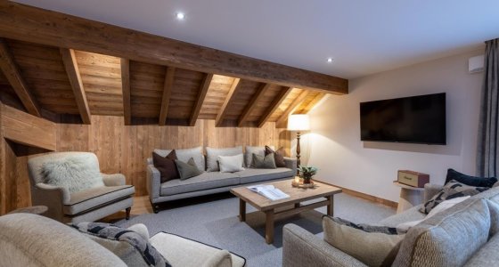 Lounge with exposed roof beams, sofa and wall-mounted TV in Apartment Le Stade, Morzine