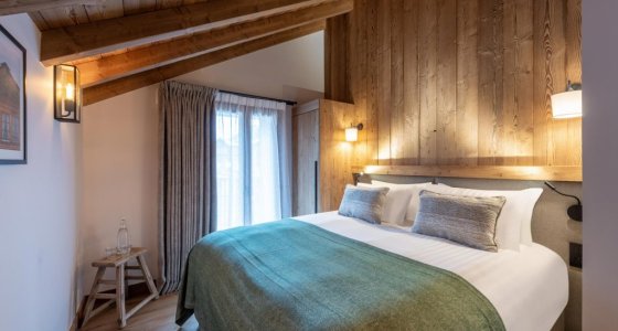 Bedroom under sloping beams with green bed runner in Apartment Le Stade, Morzine