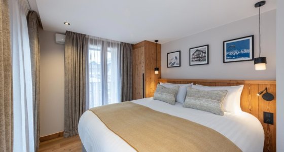 Double bedroom with cream bed runner and curtained window in Apartment Chamossière, Morzine