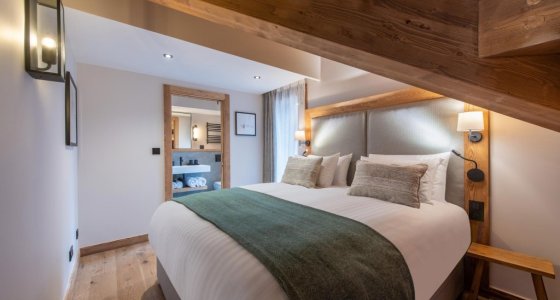 Double bedroom with green bed runner and warm timber details in Apartment Chamossière, Morzine