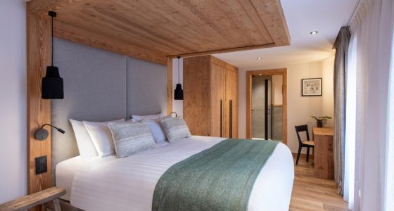 Bedroom with timber headboard wall and green bed runner in Apartment Chamossière, Morzine
