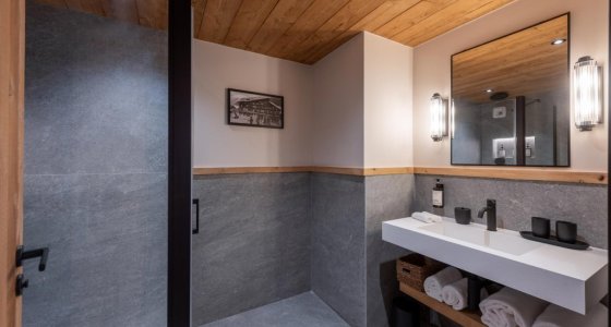 En-suite bathroom with grey tiled wall and white basin in Apartment Chamossière, Morzine