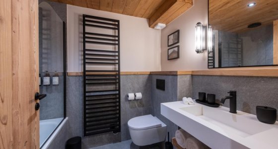 Bathroom with bath, white basin and black heated towel rail in Apartment Chamossière, Morzine