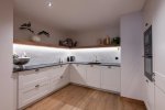 Fully equipped kitchen with white cabinets and built-in oven in Apartment Abeille, Morzine