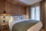 Double bedroom with olive-green throw and tall curtained windows in Apartment Abeille, Morzine