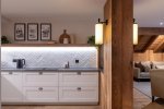 Kitchen with white cabinets, herringbone splashback and timber pillar in Apartment Le Stade, Morzine