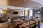 Long dining table, sofa and TV in the open-plan living space in Apartment Chamossière, Morzine