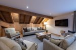 Lounge with exposed roof beams, sofa and wall-mounted TV in Apartment Le Stade, Morzine