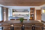 Wooden dining table surrounded by chairs with kitchen beyond in Apartment Chamossière, Morzine
