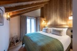 Bedroom under sloping beams with green bed runner in Apartment Le Stade, Morzine