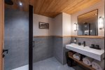 En-suite bathroom with grey tiled wall and white basin in Apartment Chamossière, Morzine