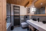 Bathroom with bath, white basin and black heated towel rail in Apartment Chamossière, Morzine